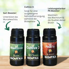 Produktfoto von BioTka Düngemitteln: Start Booster, Cultiva 3 und Final Top, auf einem Holztisch mit grünem Hintergrund, die Flaschen zeigen kräftige Farben und detaillierte Etiketten
